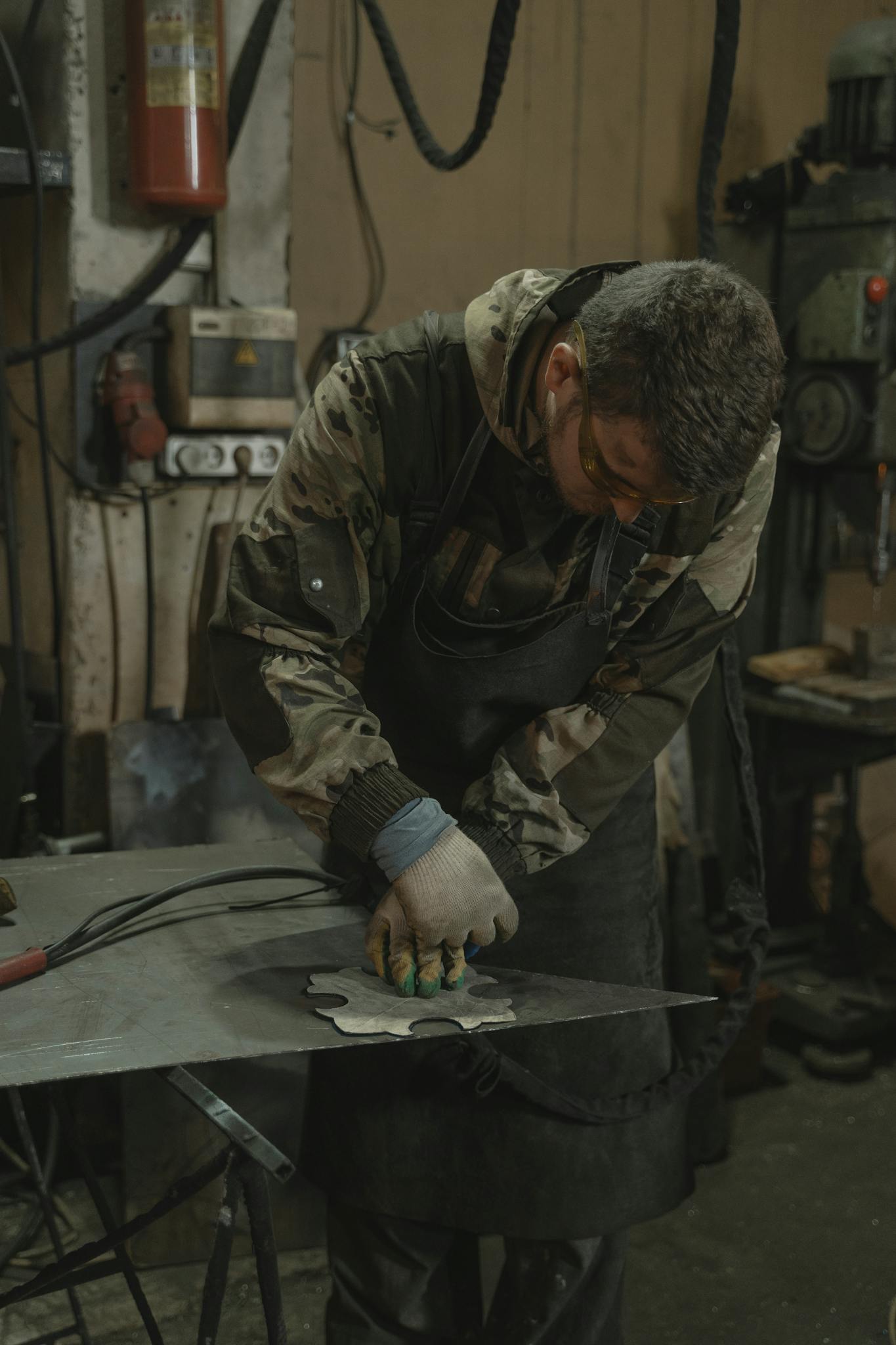 A skilled craftsman using tools to shape metal in an industrial workshop.
